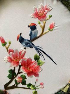 two birds on a branch with flowers painted on the back side of an embroidered pillow