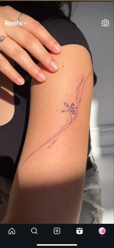 a woman's arm with a small flower tattoo on the left side of her arm