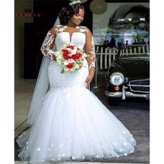 a woman standing in front of a car wearing a wedding dress with flowers on it