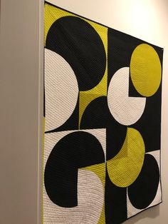 a large black and yellow quilt hanging on the wall