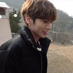 a young man in a black jacket is looking at his cell phone while standing outside