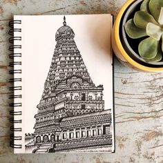 a drawing of a building on top of a table next to a potted plant