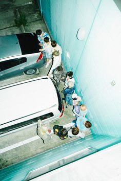 a group of people standing next to each other near parked cars