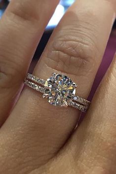 a woman's hand with a diamond ring on it and a wedding band around her finger