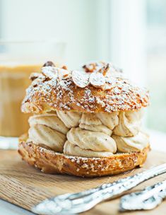 a stack of doughnuts sitting on top of a wooden cutting board next to a cup of coffee