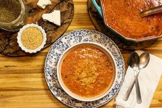 a bowl of soup on a plate next to two bowls of cheese and other food