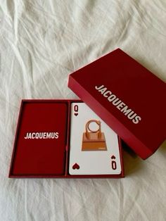 a red box that is open and sitting on top of a white sheet with the words jacquemus in it