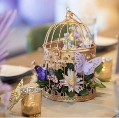 a birdcage filled with flowers and butterflies on top of a dining room table