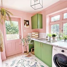 a kitchen with pink walls and green cabinetry has a potted plant on the counter