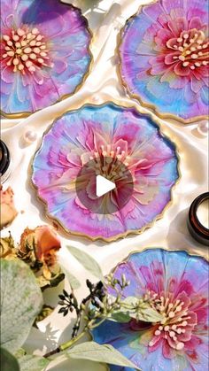 some pink and blue flowers are on top of each other in the center of three plates