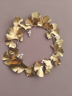 a gold wreath with leaves and pearls hanging on the wall