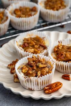 several cupcakes on a white plate with pecans and nuts in the background