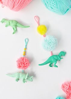 crochet pom - poms and toy dinosaurs on white surface