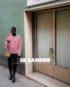 a woman is walking down the street in front of a store with her cell phone