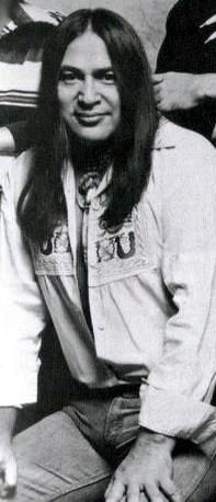 an old black and white photo of a man with long hair sitting on a couch