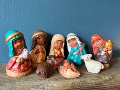 a group of nativity figurines sitting on top of a wooden table next to a blue wall