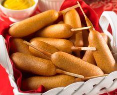 hot dogs on skewers in a basket with dipping sauce