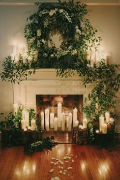 the fireplace is decorated with candles and greenery