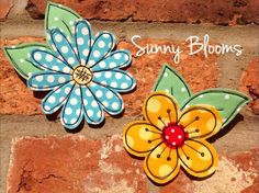 two flower brooches sitting on top of a brick wall next to each other