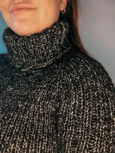 a woman wearing a black and white turtle neck sweater with an over sized cowl