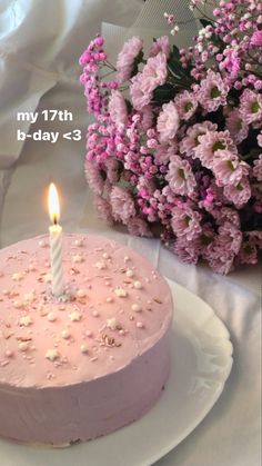 a pink cake sitting on top of a white plate next to a bouquet of flowers