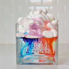 a glass vase filled with lots of colorful liquid and clouds on top of each other