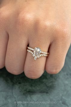 a woman's hand with a diamond ring on top of her finger and the other hand holding an engagement ring