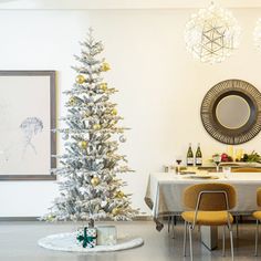 a white christmas tree sitting in the middle of a room next to a dining table