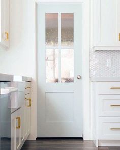 a white door in a kitchen next to a stove top oven and cabinets with gold handles