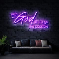 a couch sitting in front of a brick wall with a neon sign above it that says, with god all things are possible