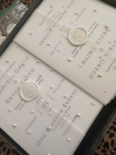 two white wedding cards with pearls on them