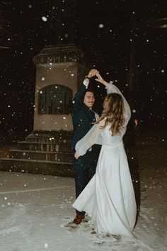 a bride and groom dancing in the snow