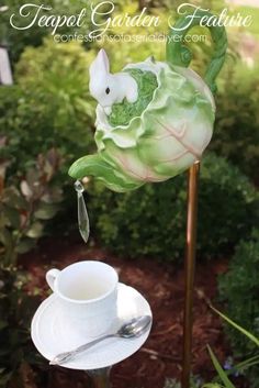 a teacup and saucer sitting on top of a metal stand in the garden