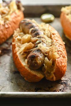 two hot dogs on buns with sauerkraut, onions and pickles