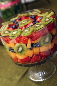 a glass bowl filled with sliced fruit and kiwis on top of each other