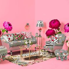 a living room filled with furniture and flowers on top of a pink wall next to two tables