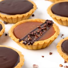 several chocolate tarts are sitting on a white surface