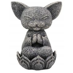 a statue of a cat sitting on top of a white surface with its eyes closed