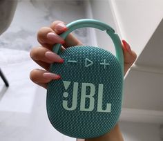 a woman holding a jbl portable speaker in her hand with the word jbl on it