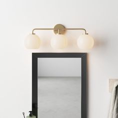 a bathroom mirror with three lights above it and a towel rack in front of it