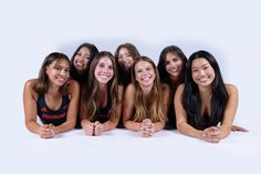 a group of young women sitting next to each other in front of a white background