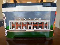 a painted lunch box sitting on top of a wooden table in front of a building