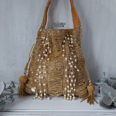 -GOLD PEARL BEADED POTLI HANDBAG-  Regal designer clutch with heavy hand embroidery is sure to turn heads! Elegantly embellished with pearl tassels and BEADS in beautiful warm tones on a matte gold base. Fully stitched with hand embellishments all over. Indo-western potli handbag comes with stitched top handle with bead work and soft velvet internal lining.  PERFECT clutch sized to fit most  phones and accessories in style! Makes a great gift too! Our beautiful Indo-western design done in our mo Pearl Tassels, Bridal Purse, Designer Clutch, Western Design, Indo Western, Gold Stone, Gold Pearl, Phones And Accessories, Matte Gold