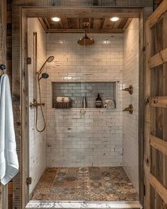 a walk in shower sitting inside of a bathroom next to a wooden door and tiled floor