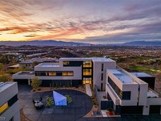 an aerial view of a modern home with mountains in the background at sunset or dawn