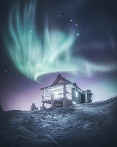 the aurora bore is shining brightly in the sky above a small cabin on snow covered ground