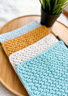 a potted plant sitting on top of a wooden table next to a crochet dishcloth