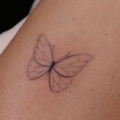 a small butterfly tattoo on the back of a woman's shoulder