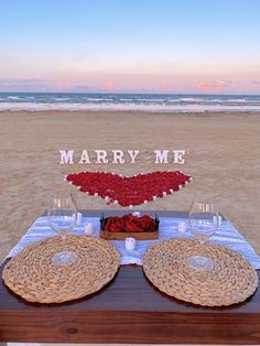 a table set up on the beach with place settings for two people to sit at