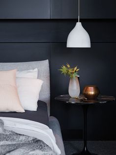 a bed room with a neatly made bed next to a night stand and a vase